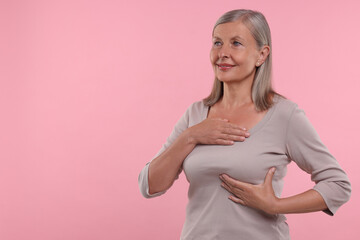 Sticker - Beautiful senior woman doing breast self-examination on pink background, space for text