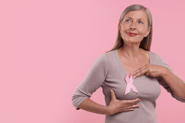 Poster - Beautiful senior woman with pink ribbon on color background, space for text. Breast cancer awareness