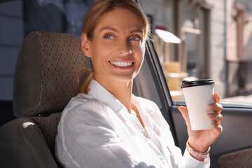 Wall Mural - Coffee to go. Happy woman with paper cup of drink in car