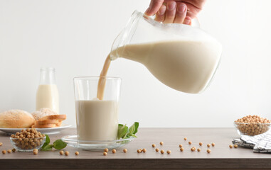 Wall Mural - Filling glass with soy milk from a jug white isolated