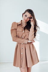 Poster - Beautiful young woman in beige dress in white room