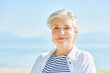 Outdoor summer closeup portrait of happy and healthy mature 50 - 55 year old woman enjoying nice sunny day by the lake or sea, active lifestyle