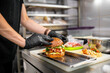 © pavel siamionov - chef hand cooking cheese burger with vegetables and meat on restaurant kitchen