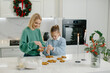 © dsheremeta - Mother and daughter decorate Christmas cookies in the kitchen.