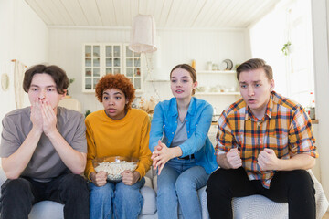 Wall Mural - Group of friends watching sport match soccer football game on tv. Happy football fans celebrating victory at home. Friendship sports entertainment concept. Diverse buddies having fun together at home