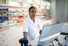 Senior Female Pharmacist Working On Computer At Drugstore