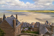 Mont Saint Michel, France. View to the village, central square, old historical houses and low tide ocean.
