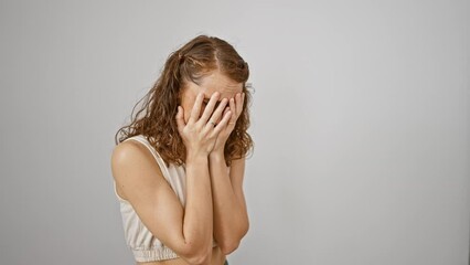 Poster - Fearful, young woman standing isolated, tearfully covering her face with her hands, portraying a painful expression of sadness and depression against a stark white background