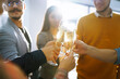 © maxbelchenko - Business people celebrate with glasses of champagne in the office at a corporate event. A group of young people are having fun in the office. Holidays, business concept.