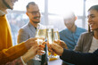 © maxbelchenko - Business people celebrate with glasses of champagne in the office at a corporate event. A group of young people are having fun in the office. Holidays, business concept.