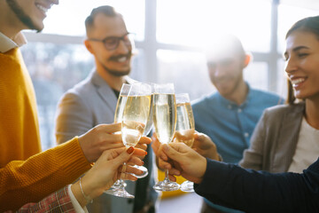 Business people celebrate with glasses of champagne in the office at a corporate event. A group of young people are having fun in the office. Holidays, business concept.