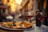 Fototapeta Uliczki - Pizza, wine bottle, wineglasses and spice oil on the restaurant table outdoors, background of narrow old Italian streets 