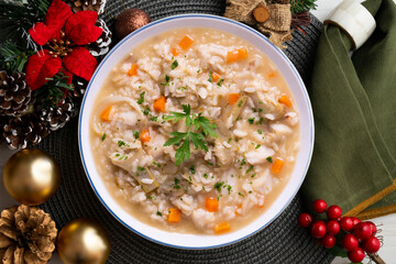 Poster - Soupy rice with artichokes and carrots. Typical Spanish gastronomy dish.  Christmas food served on a table decorated with Christmas motifs.