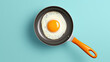 Fried egg on small pan isolated on turquoise background.