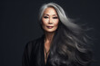 Beauty portrait of an attractive sensual mature Asian woman with long gray hair over black background