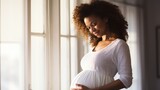 Fototapeta  - Pregnant afro american woman gripping her stomach and holding hands