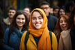 A Muslim woman in a hijab with a happy face stands and smiles with a confident smile against the background of other people