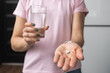 Young woman taking medicine pill, painkiller or antibiotic, holding glass of water