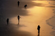 Menschen am Sandstrand im goldenen Licht des Sonnenuntergangs, fotografieren oder genießen ihren Urlaub