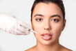 © Pixel-Shot - Young woman receiving lip injection on light background, closeup