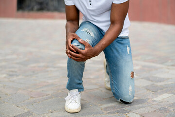 a man touch his sprained leg outdoors, feel pain