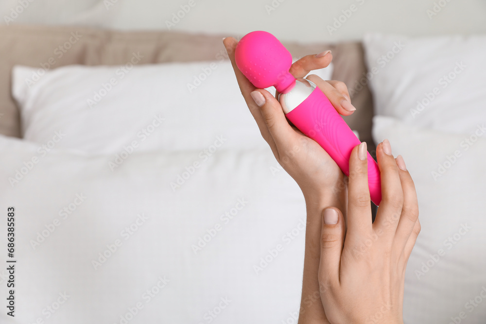Woman with vibrator in bedroom, closeup