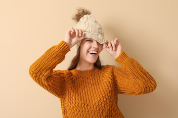 Canvas Print - Young woman in winter clothes on beige background