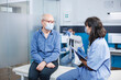 © DC Studio - Nurse practitioner is taking notes during a session with senior man. During covid 19 epidemic, an elderly male patient attending a healthcare assessment with a medical assistant.