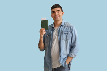 Wall Mural - Happy young man with passport on blue background