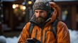 A rugged individual clad in a winter cap and insulated jacket concentrates on his smartphone, a scene well-suited for showcasing the reliability of outdoor technology or winter apparel
