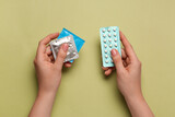 Fototapeta  - Woman with condoms and contraceptive pills on olive background, top view. Choosing birth control method