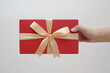 © David - Male hands holding a small red gift box wrapped with gold ribbon. Isolated white background. Selective focus. Christmas Concept.