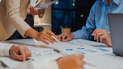 Wall Mural - Closeup happy young Asia businesspeople meeting brainstorming some new ideas about project to his partner working together planning success strategy enjoy teamwork in small modern home office night.