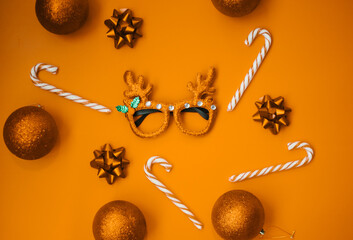 Wall Mural - Christmas masquerade glasses with deer antlers, balls, lollipops on a golden background. The concept of a Christmas party. A fun holiday. Decoration for children and adults.