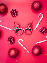 Wall Mural - Christmas fancy dress glasses with deer antlers, balls, lollipops on a pink background. The concept of a Christmas party. A fun holiday. Decoration for children and adults.