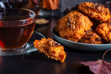 Wall Mural - Carrot cookies with walnuts and tea in a cup against a dark background