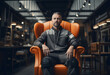 Portrait of a carpenter in gray work clothes sits on orange leather armchair in a factory shop
