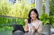 © PBXStudio - Attractive young Asian woman with tablet and credit card She found success by shopping online in the outdoor seating area at a coffee shop.