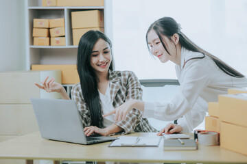 Wall Mural - Two beautiful Asian women are happy and excited after receiving a new order from an SME customer. Commercial inspection. online marketing Boxes for entrepreneurs, SME sellers and independent online sa