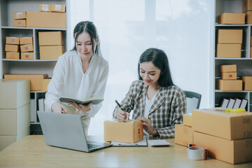 Wall Mural - Two beautiful Asian women are happy and excited after receiving a new order from an SME customer. Commercial inspection. online marketing Boxes for entrepreneurs, SME sellers and independent online sa