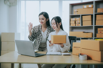 Wall Mural - Two beautiful Asian women are happy and excited after receiving a new order from an SME customer. Commercial inspection. online marketing Boxes for entrepreneurs, SME sellers and independent online sa