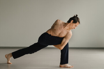 a man with a naked torso does yoga in the gym. the concept of a healthy lifestyle