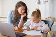 © lordn - Mother and daughter learning together at home, sitting at the desk in front of a computer. Back to school