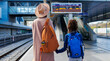 © zhukovvvlad - Mom and child with backpacks are waiting for the train on the platform. The family is ready to travel.