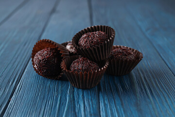 Wall Mural - Brigadeiro in paper forms on blue wooden background, close up