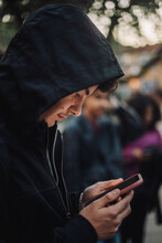 Side View Of Teenage Boy Wearing Hoodie And Using Smart Phone