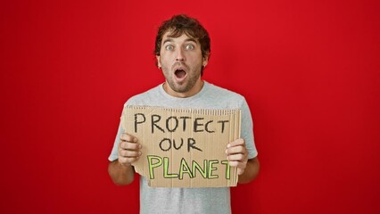 Poster - Shocked and amazed young man with 'protect our planet' banner! fearful yet excited expression on his face, isolated against red backdrop.