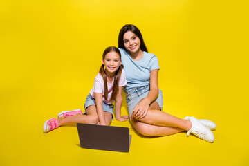 Canvas Print - Photo of two best friends using netbook teenager help younger sister with homework isolated over shine color background