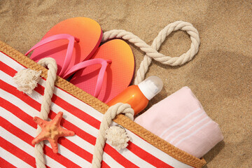 Sticker - Stylish striped bag with beach accessories on sand, flat lay