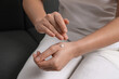 © New Africa - Woman applying cosmetic cream onto hand on sofa, closeup